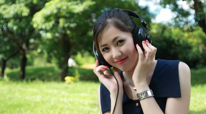 Woman Listens to Earphones in Open Grassfield